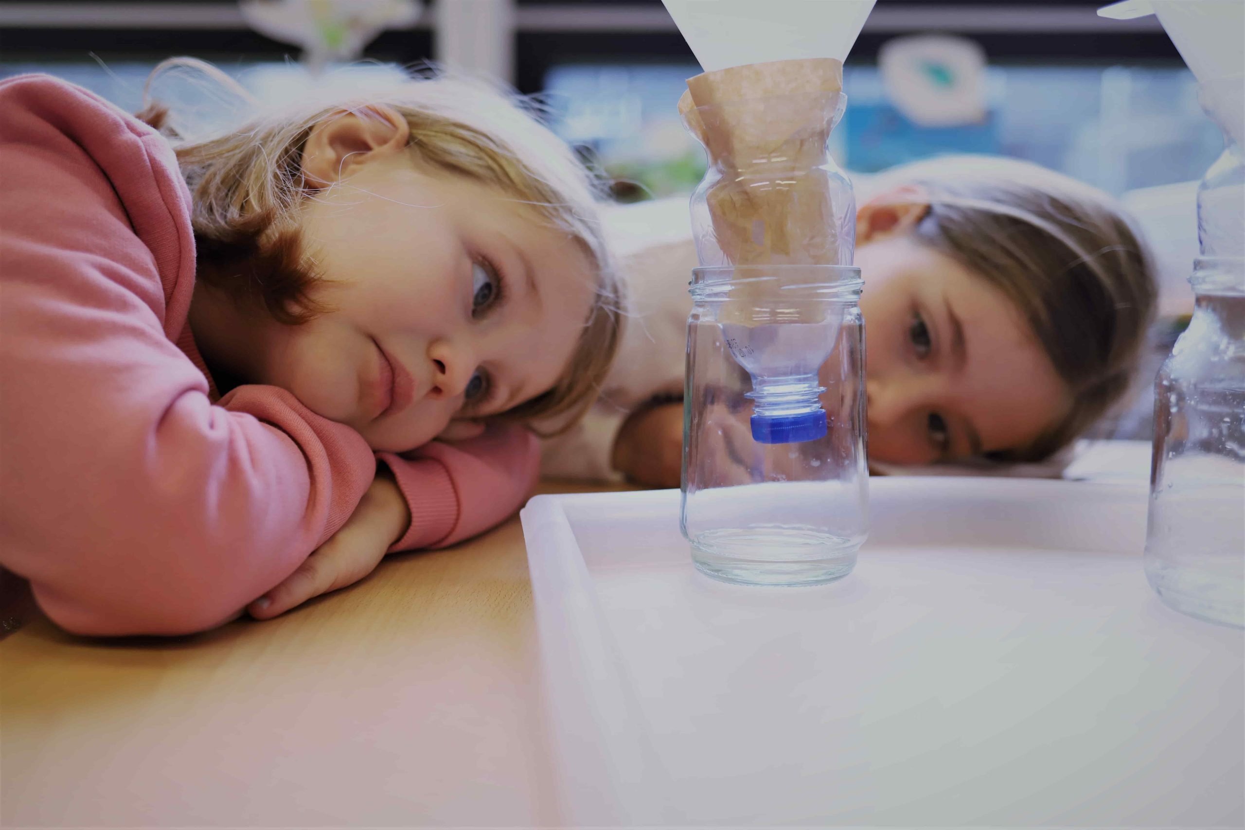 Zwei Kinder schauen ihrem Schmutzwasserexperiment beim Tropfen zu