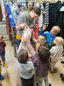 Mitarbeiterin des Jungen Staatstheaters Karlsruhe zeigt einer Gruppe von Kindern das Kostüm der Fee Amarillis