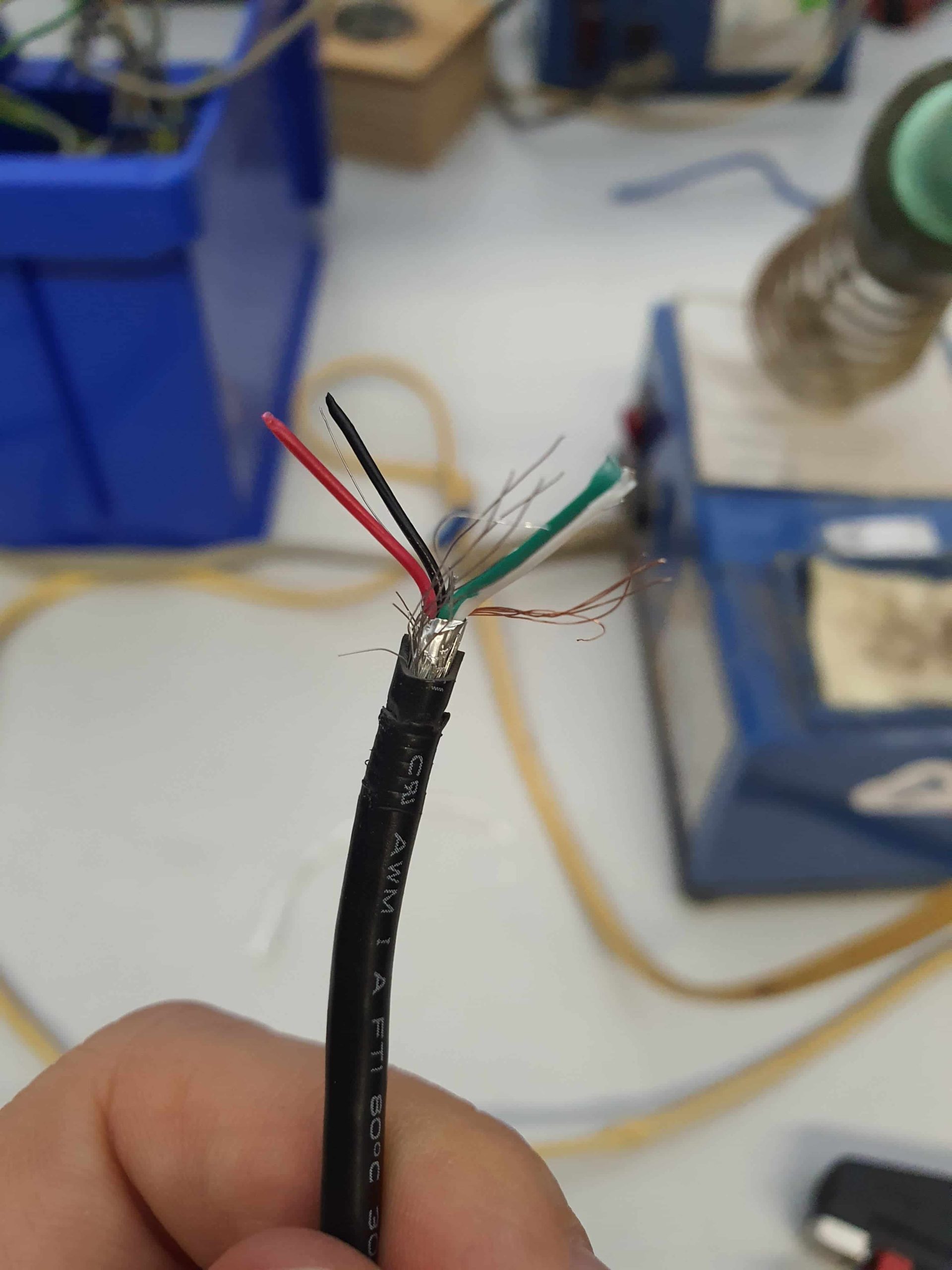 Freigelegte Kabel in schwarz, rot und grün am Ende eines isolierten Kabelstrangs.